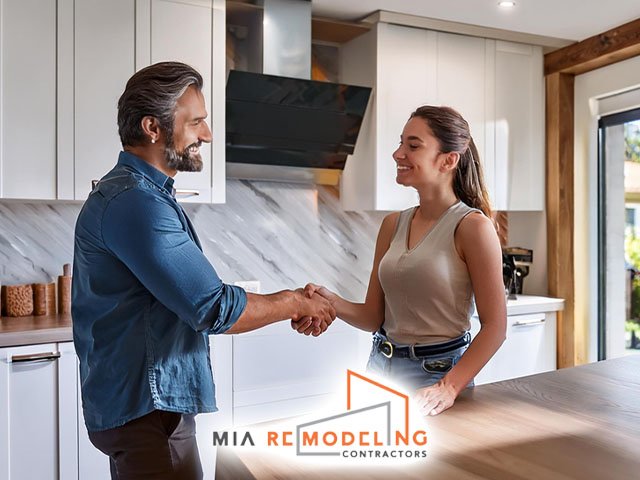 mia remodeling contractors technician professional shaking hands smiling with satisfied female customer in newly remodeled beautiful modern kitchen residential home