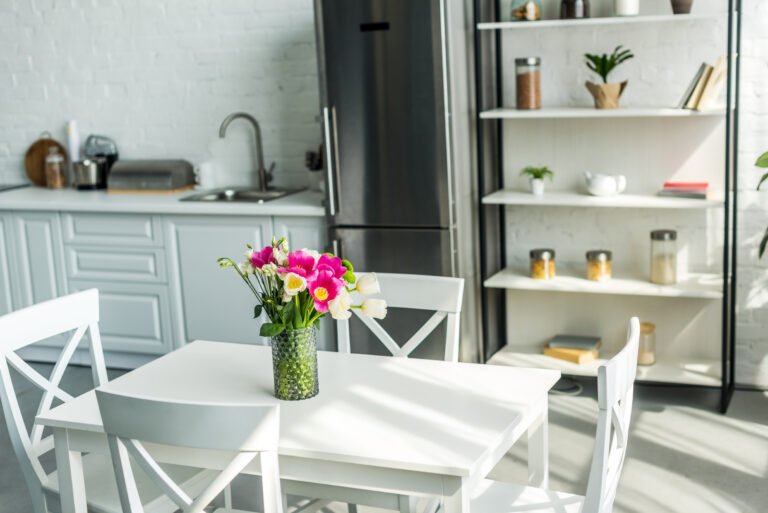 interior of modern light kitchen with bouquet on wooden table
