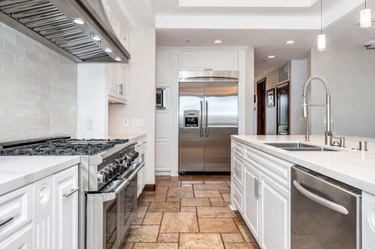 a large modern white kitchen with tiled flooring and stainless steel appliances