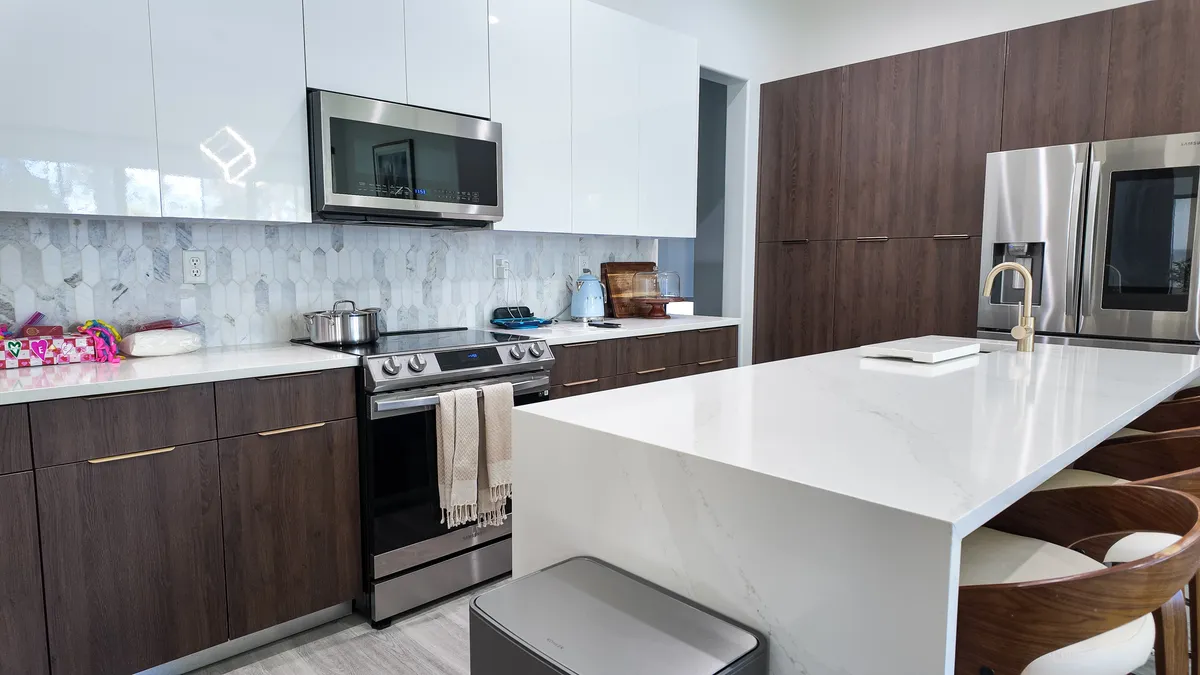 Dark walnut kitchen with white waterfall island and brass fixtures in Pembroke Pines, FL