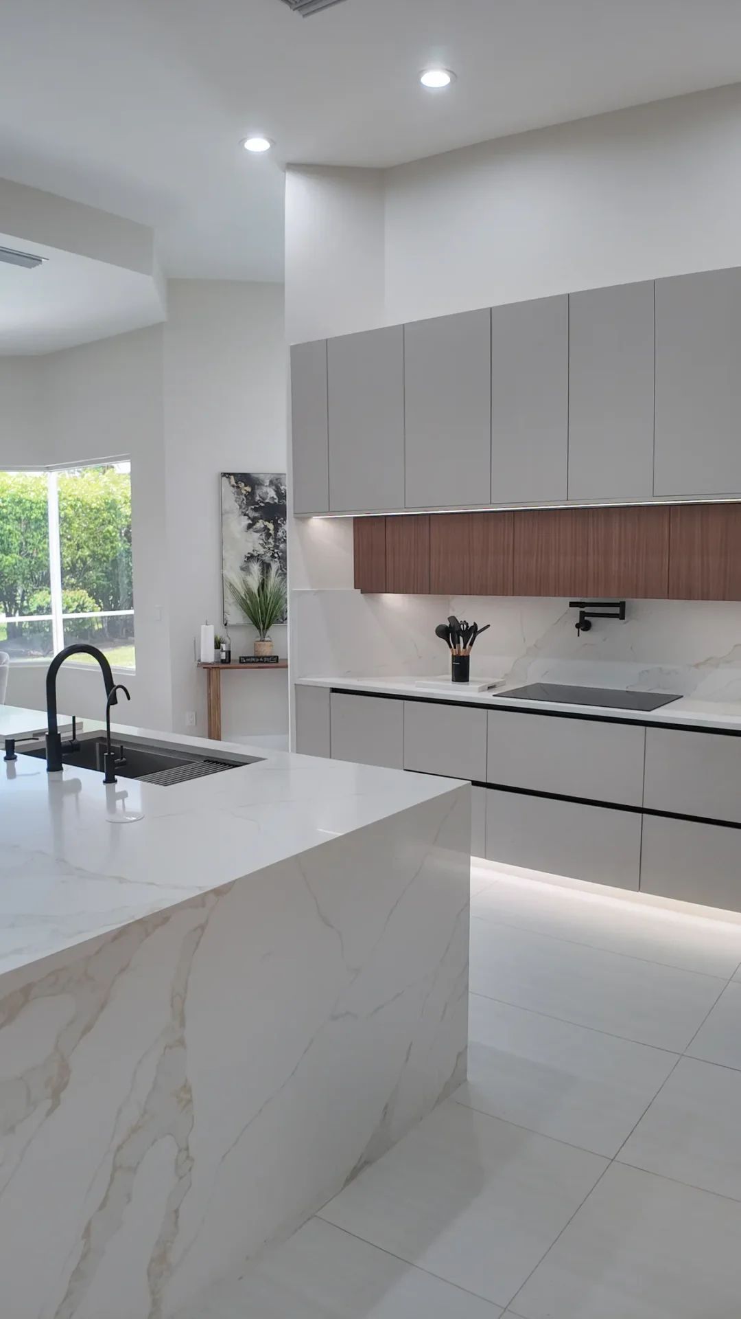 Kitchen with a large waterfall island and walnut cabinetry in a Coral Springs, Florida remodel.