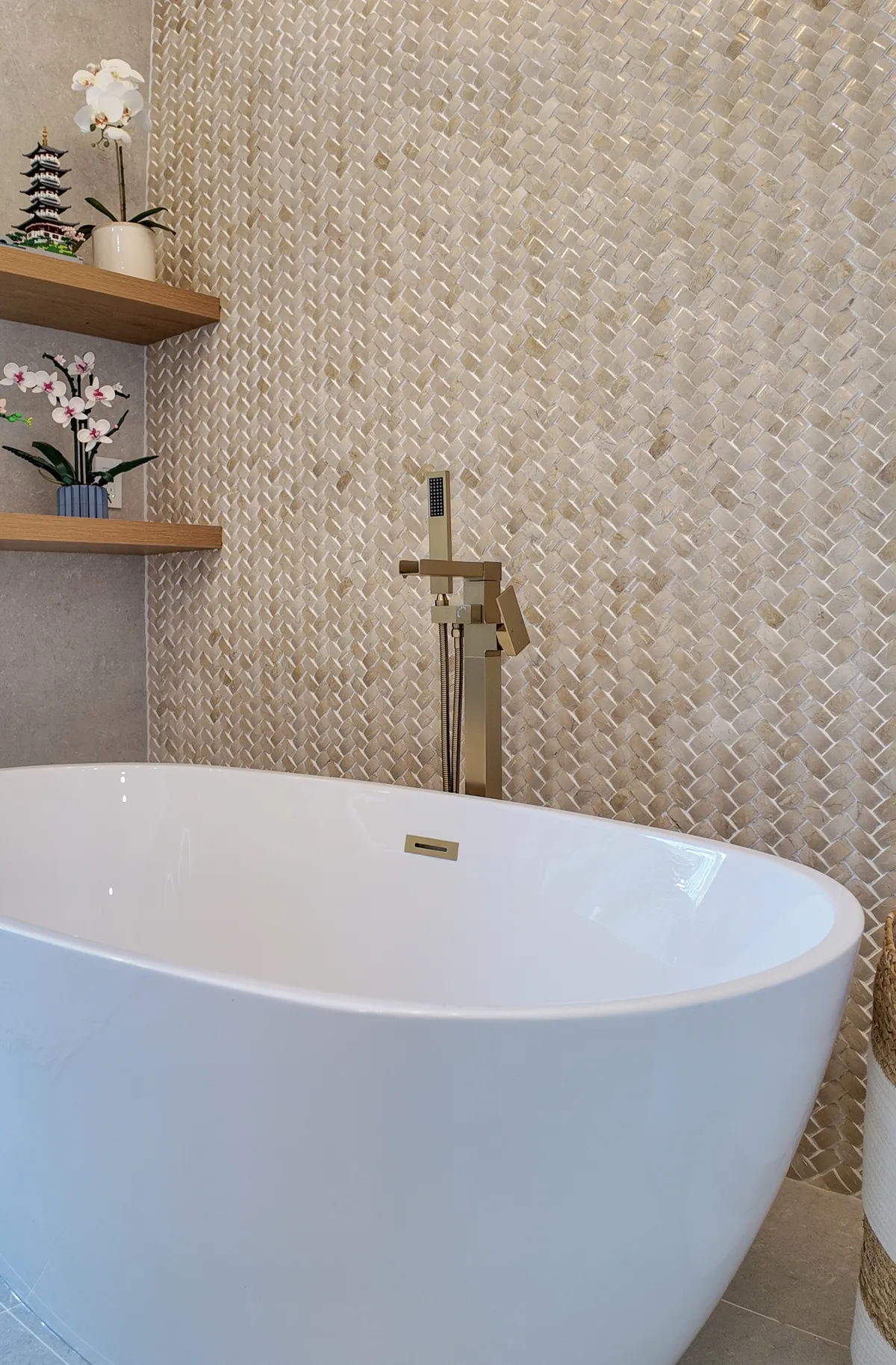 Freestanding soaking tub with brushed gold filler and ivory herringbone mosaic wall, Palm Beach Gardens