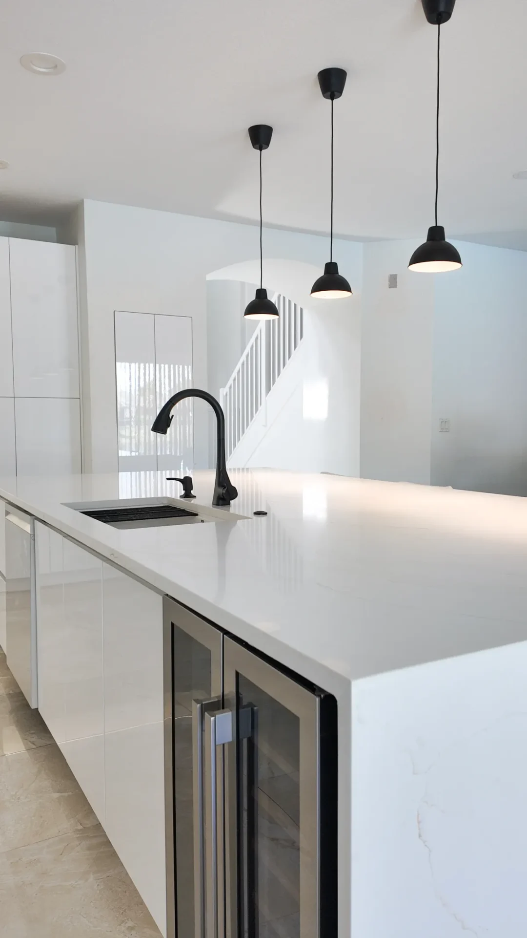 Kitchen with a waterfall quartz island and wood-grain cabinetry in Palm Beach Gardens, Florida.