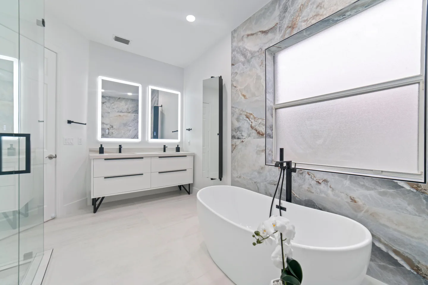 Renovated condo bathroom with marble-look tile, a walk-in shower and a freestanding tub