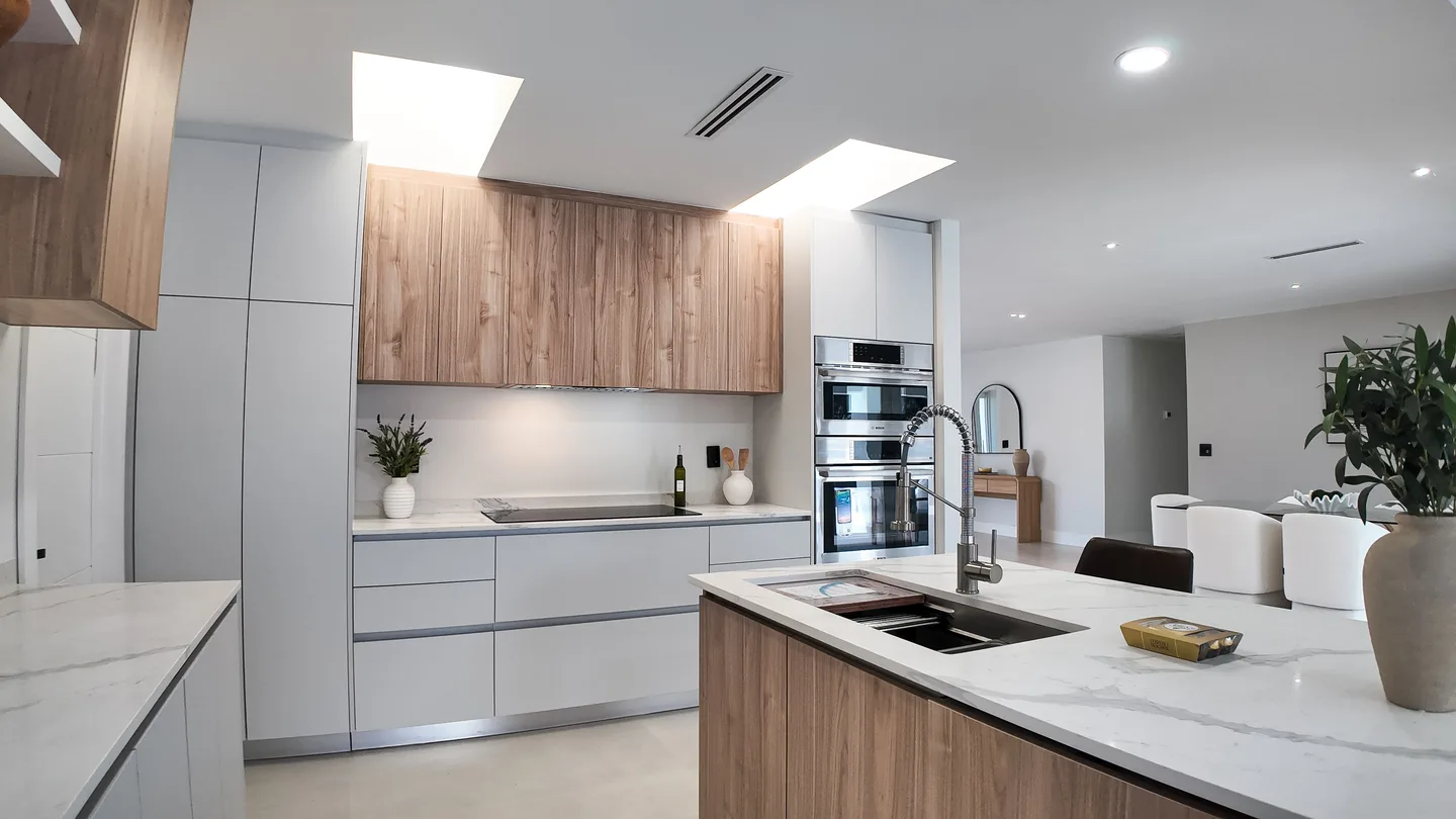 Open-plan condo kitchen remodel with a stone island and wood cabinets