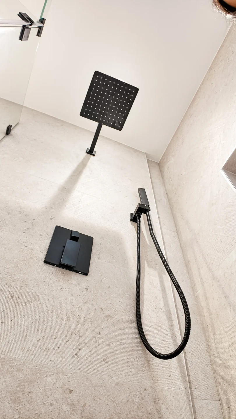 Walk-in shower with matte black fixtures and marble-look tile in a Miami bathroom remodel