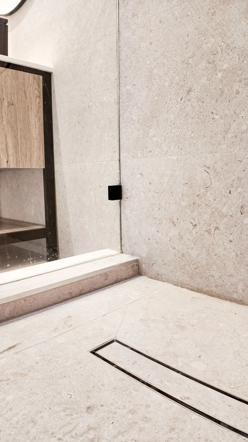 Curbless walk-in shower with a linear drain and marble-look floor tile