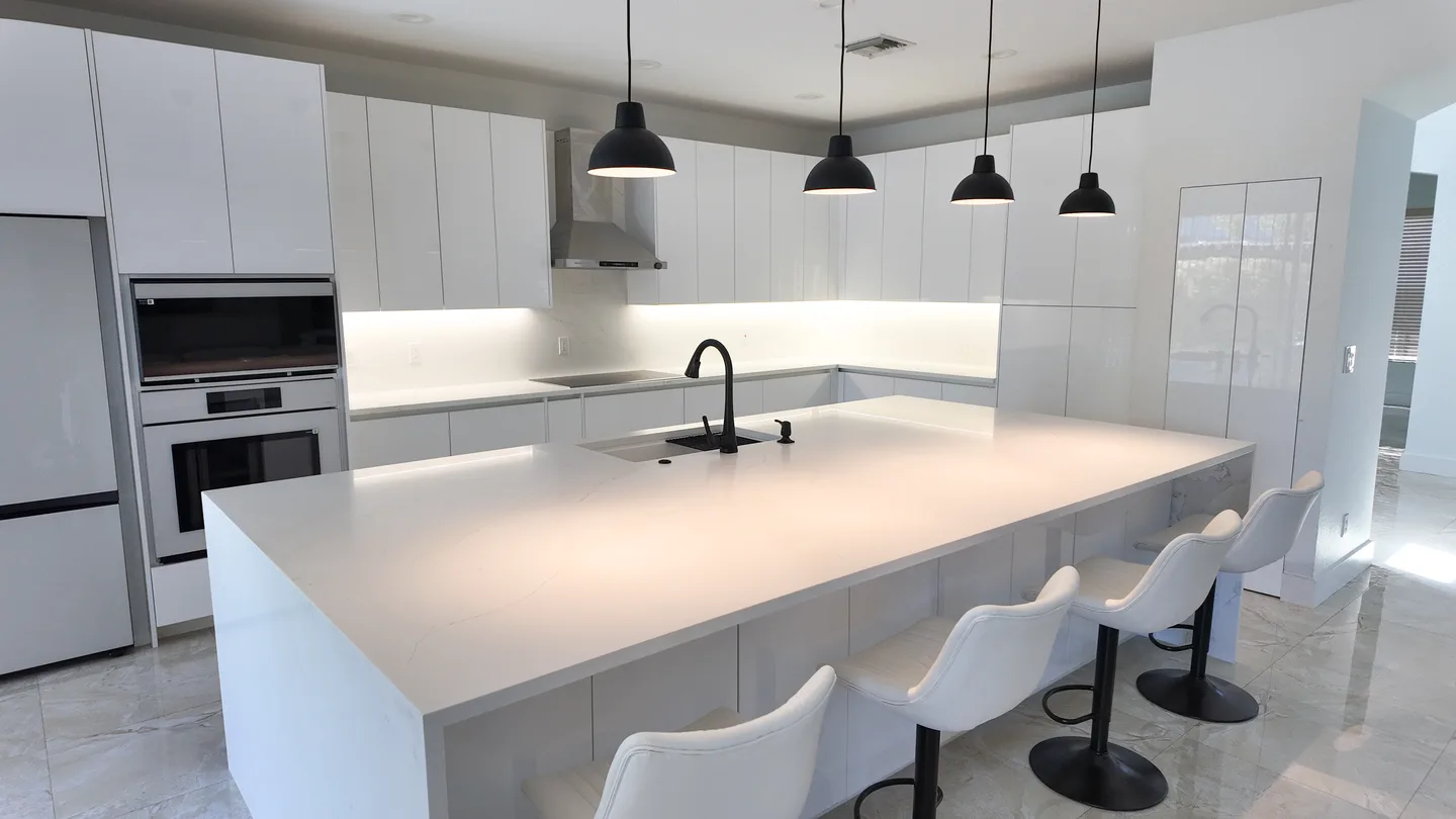 White kitchen remodel with a waterfall island and black pendant lights in Weston, Florida