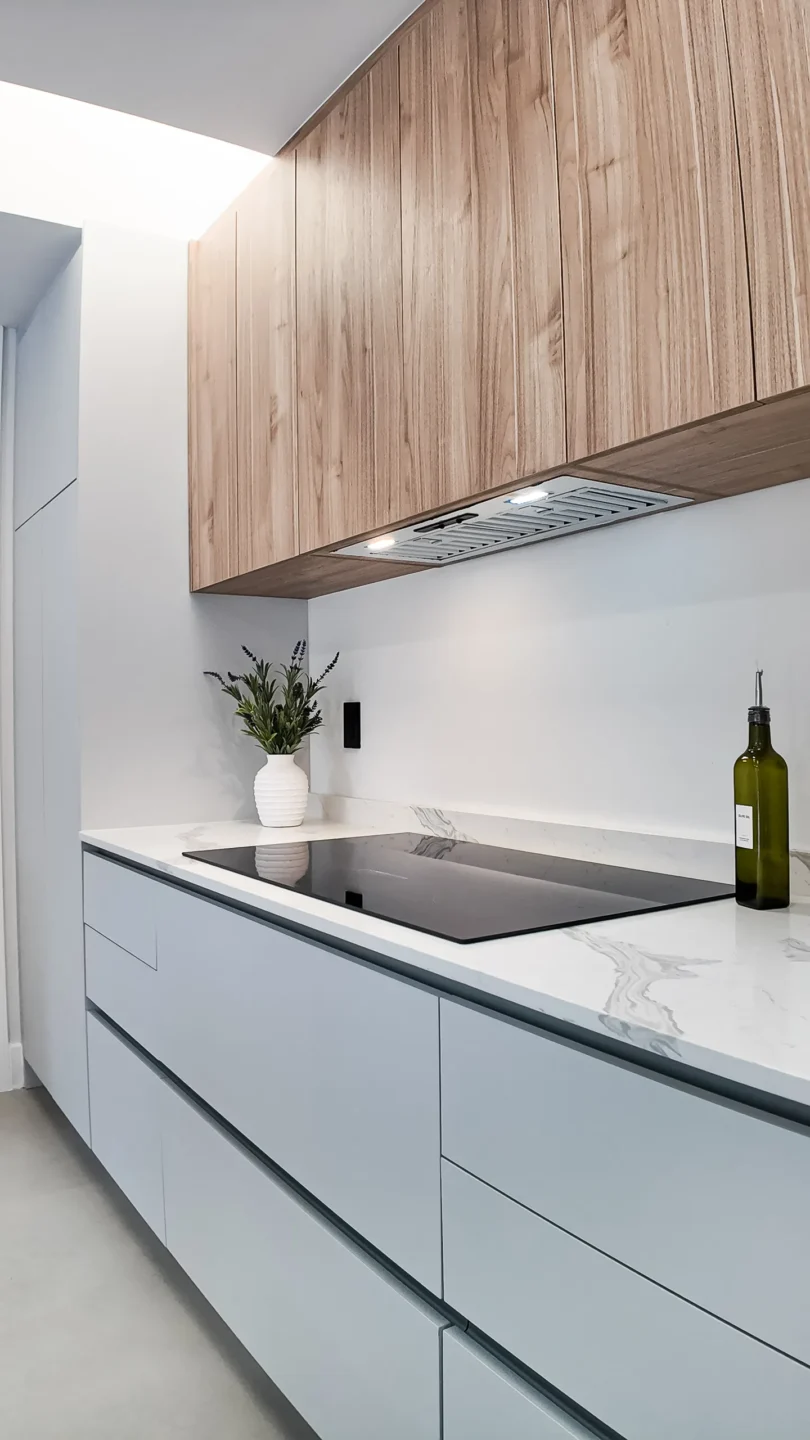Wood upper cabinets and white base cabinets with an integrated range hood